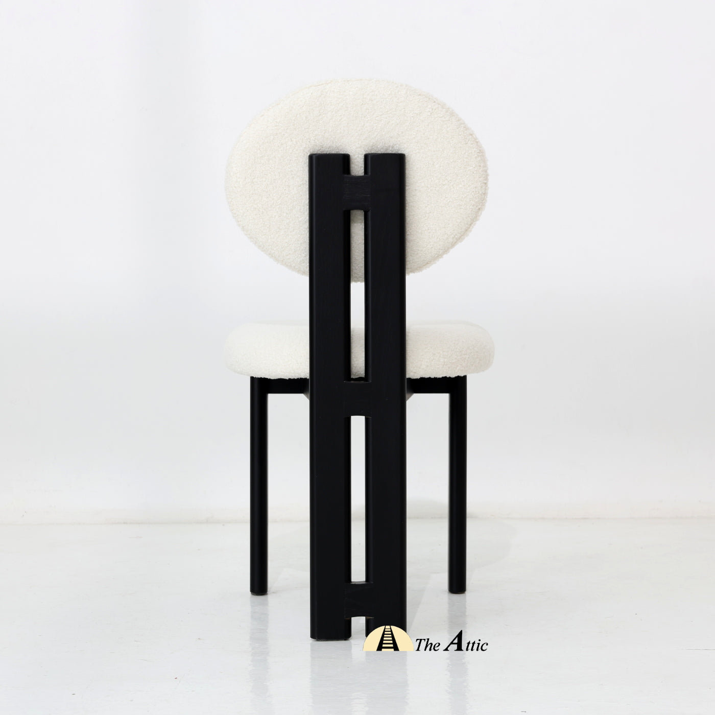 A wooden dining chair with padded seat and backrest, made from black-stained oak wood and upholstered in boucle fabric.