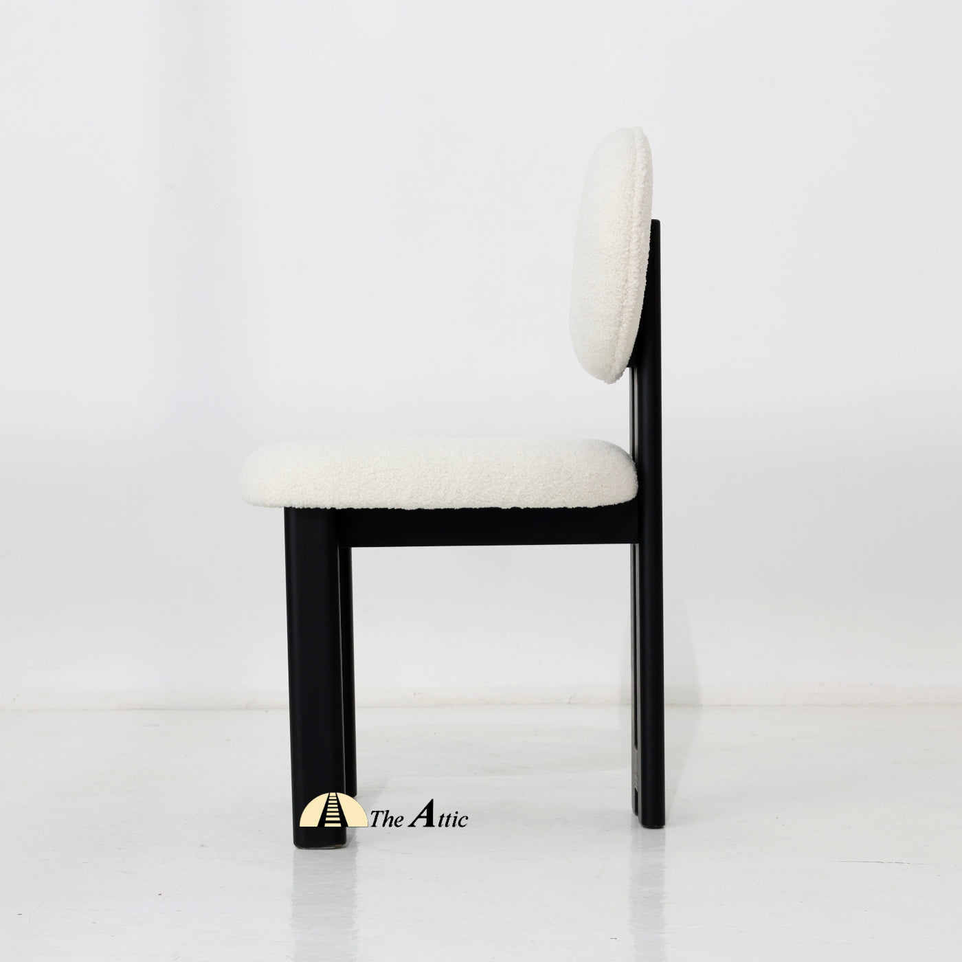 A wooden dining chair with padded seat and backrest, made from black-stained oak wood and upholstered in boucle fabric.