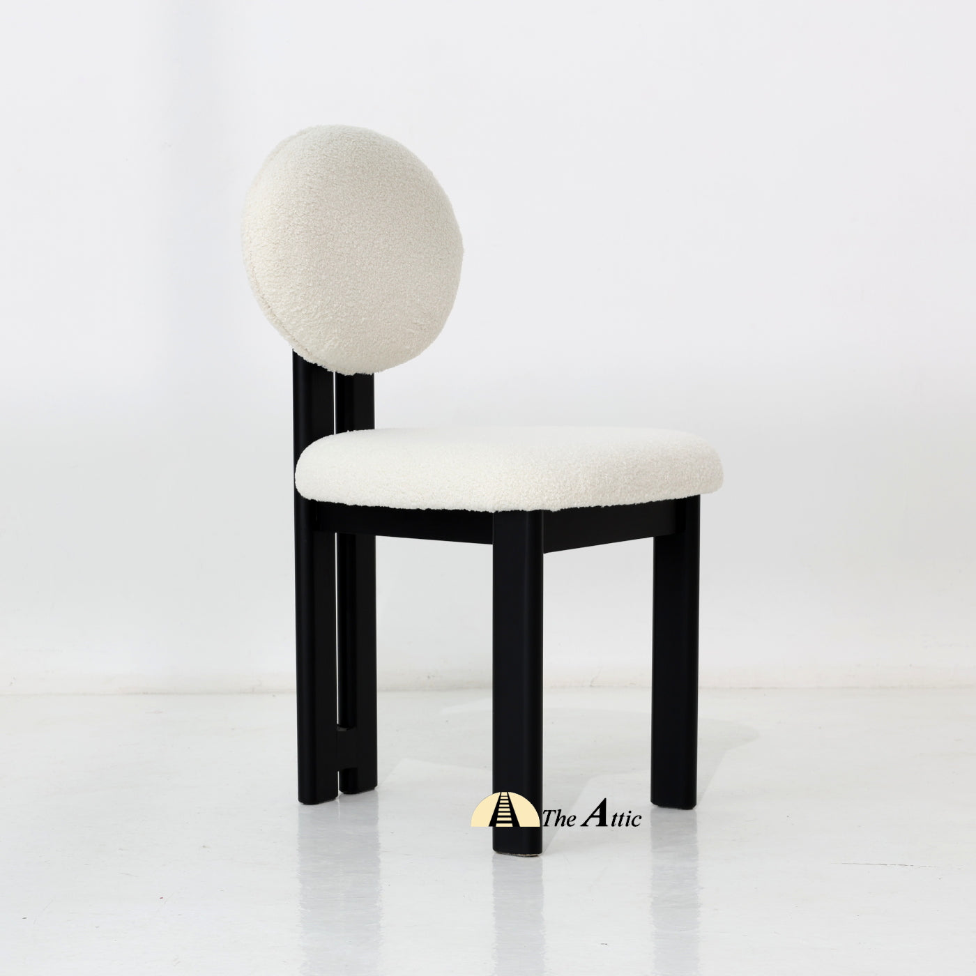 A wooden dining chair with padded seat and backrest, made from black-stained oak wood and upholstered in boucle fabric.