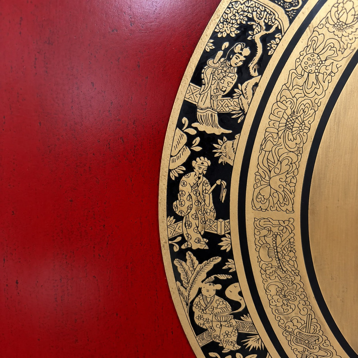 Close-up of the decorative medallion hand-painted on the cabinet showing gold-toned illustrated figures and floral motifs